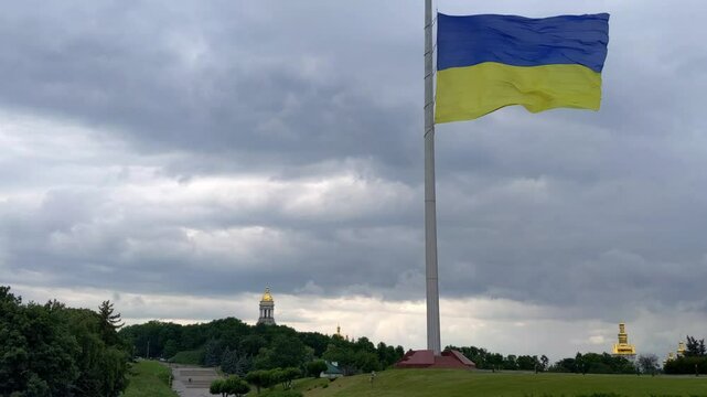 Ukrainian flag on flagpole. Kyiv cityscape