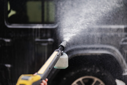 Power washing a car with a pressure cleaner tool