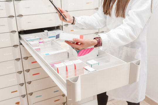 Close up of female Pharmacist scanning and organizing medicine boxes in drawer at pharmacy storage