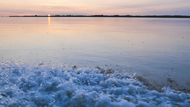 Whitewater splashing from bow of boat navigating river at sunset, creating beautiful texture Amur River