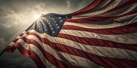American flag waves proudly against a dramatic sky with the sun shining through the clouds