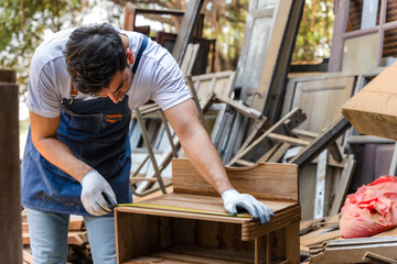 Carpenter man using measuring tape working in carpentry workshop