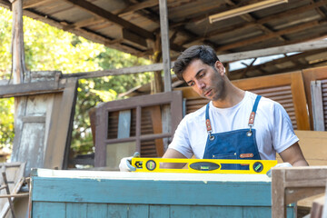 Carpenter man using bubble water lever working in carpentry workshop