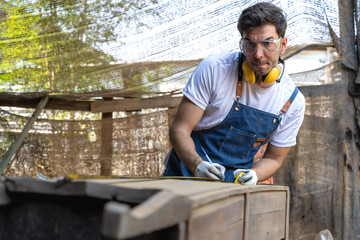 Carpenter man measuring wood plank working diy furniture in carpentry workshop