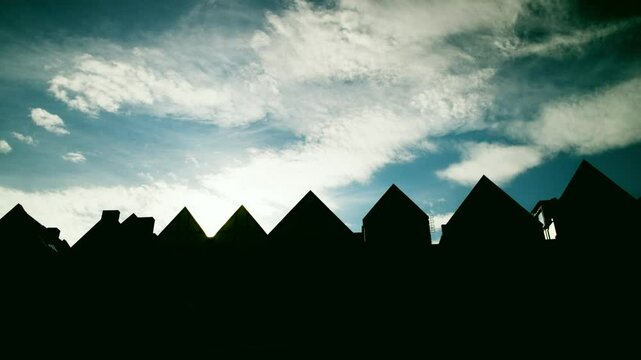 Row of tudor houses silhouetted against a cloudy sky. time-lapse