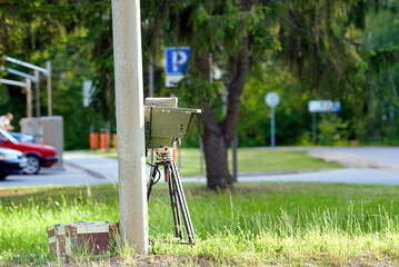Speed Radar. Mobile speed control camera. Speed radar on tripod positioned near street light post for traffic enforcement and monitoring. Traffic control device. Automated vehicle speed control
