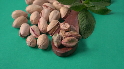 Pistachios or Pista nuts decorated with green leaves. plain background, top view.Flat lay.