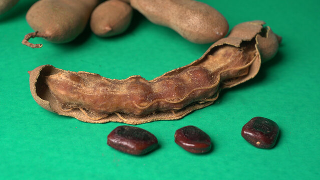 Tamarind fruit with seed isolated on green background with copy space for your text. Top view. Flat lay