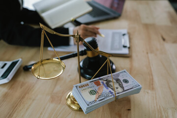 A professional is seated at a desk, with a gavel and a stack of money in the foreground, while...