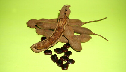 Tamarind fruit with seed isolated on green background with copy space for your text. Top view. Flat lay