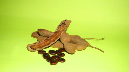 Tamarind fruit with seed isolated on green background with copy space for your text. Top view. Flat lay