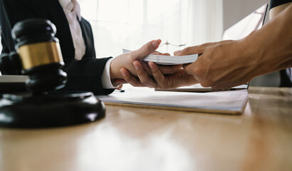 A hand holding stacks of money is shown being exchanged with another hand, implying a transaction, payment, or perhaps an illegal exchange in a legal context.