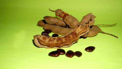 Tamarind fruit with seed isolated on green background with copy space for your text. Top view. Flat lay