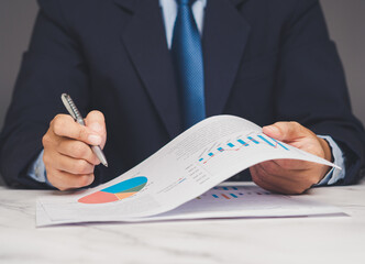 Businessman reviewing financial graphs and pie charts on paper, concept of analysis and planning