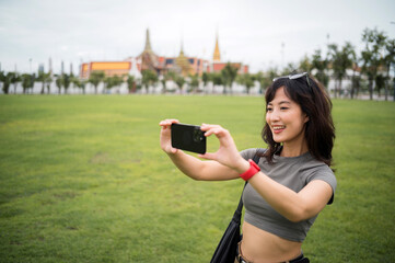 Happy southeast asian woman teenager blogger explorer on solo world travel take photo with...