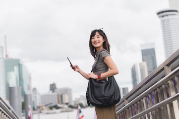 Happy young southeast asian woman teenager blogger using smartphone searching travel guide. World...