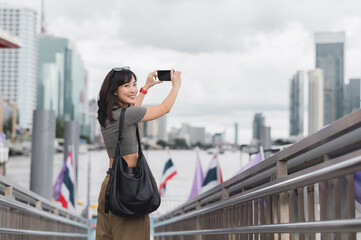 Solo southeast asian woman happy teenager blogger and world travel explorer use smartphone to take...