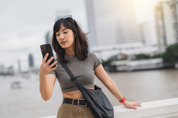 Young southeast asian woman teenager blogger using smartphone searching for guide. World travel...