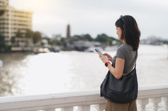 Young southeast asian woman teenager blogger world travel explorer searching smartphone map guide. Asia tourism concept local cultural experience Bangkok Thailand Chao Phraya River