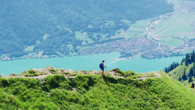 Hiker walks along the narrow Hardergrat ridge with Lake Brienz shimmering below