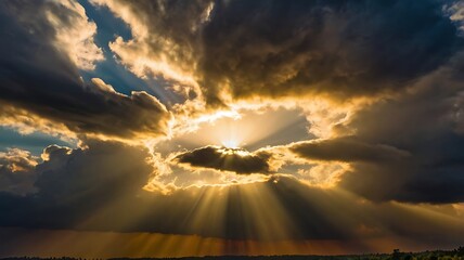 Dramatic sky with sun rays breaking through storm clouds creating a golden and ethereal sunset landscape