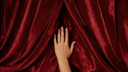 Female hand. Feminine hand with gold ring on red velvet curtain backgr