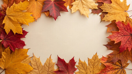 Obraz premium Vibrant arrangement of fall foliage in various shades of red, orange, and yellow forms a decorative border on a neutral background, evoking the cozy and inviting atmosphere of autumn