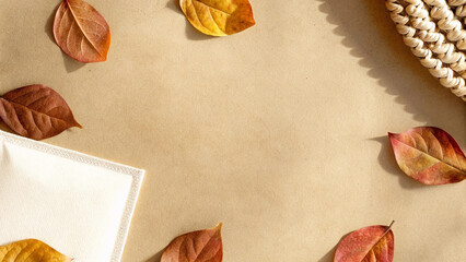 Vibrant autumn leaves in shades of red, orange, and yellow arranged on a beige background, creating a beautiful frame with ample space for text, evoking a warm fall atmosphere