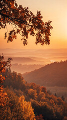 Warm sunlight illuminates layers of colorful trees and rolling hills covered with a blanket of mist during a serene autumn morning, creating a breathtaking natural panorama