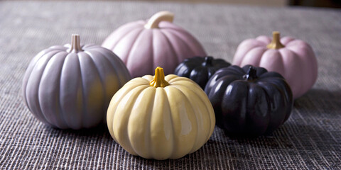 Pastel colored pumpkins are arranged on a textured surface, evoking the spirit of autumn and halloween with their varied hues and festive arrangement