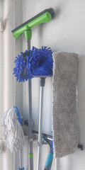 Cleaning tools organized on a wall, showcasing mops and dusters in a tidy storage space for household chores