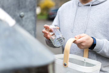 Separating garbage. Man recycling glass jar into container on town street. Sustainable lifestyle...