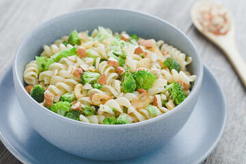 Fusilli or rotini pasta with broccoli, roasted garlic slices, chopped almonds, herbs and olive oil,...