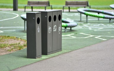 Sorting trash bins in a public park with separate containers for plastic, paper, and glass and...