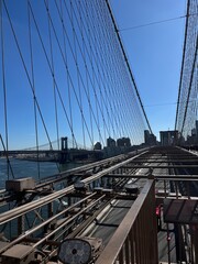 Obraz premium The iconic and infamous Brooklyn Bridge in the heart of Brooklyn, NYC on a sunny day against a blue sky.