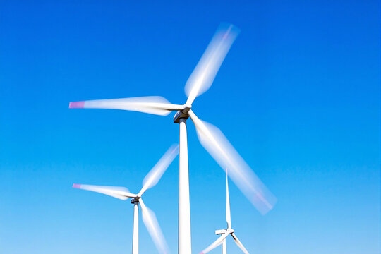 Modern wind turbines with blades in motion against a clear blue sky, generating clean and renewable electricity as a sustainable source of alternative energy, representing the future of green power