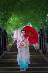 A young Asian Japanese woman in a Traditional Furisode Kimono Yukata dress costume holding a red...