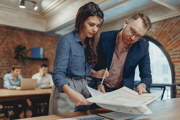 A dedicated professional duo working together on project blueprints within a stylish and modern workspace