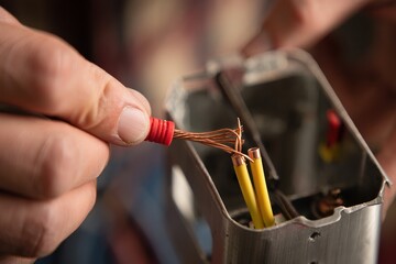 Skilled technician carefully connecting wires inside an electrical device, showcasing precision and craftsmanship in a well-lit workspace with tools and equipment surrounding the area