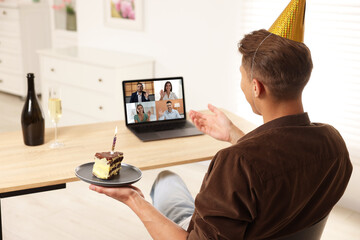 Celebrating birthday online. Man with cake having video call with friends via laptop at home