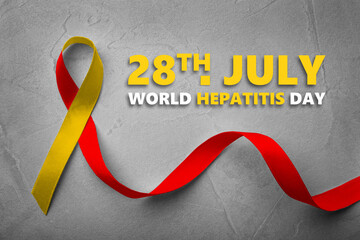 28th july World Hepatitis Day. Yellow-red awareness ribbon on grey textured background, top view