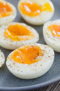 Soft boiled egg halves sprinkled with salt and pepper served on blue plate (Selective Focus, Focus one third into the image)