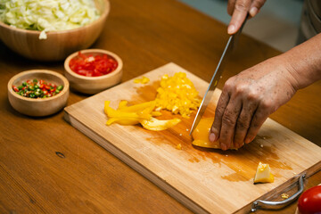 Asian man's hands cutting bell peppers in the kitchen.