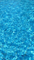 clear blue water surface with sunlight reflections creating a serene and tranquil swimming pool atmosphere for relaxation and leisure activities