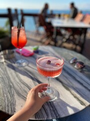 Summer vacation vibes: refreshing cocktails and snacks served outdoors in a cozy seaside or rustic cafe. Perfect moment of leisure and relaxation in the sun.

