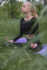Young woman meditates outdoors in lotus pose, expressing calmness and inner harmony.