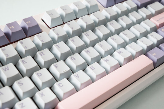 Modern mechanical keyboard on blue background. Minimal style and design keyboard. Custom build keyboard with pink and green keycap. Close up