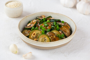 Cucumber salad with sesame seeds, green onion, soy sauce and garlic in a bowl on a light table.