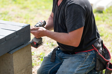 A man is drilling screws into wooden beams