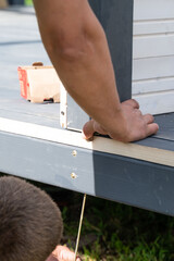 A man checks to see if the wall is level with the floor when installing a gazebo.